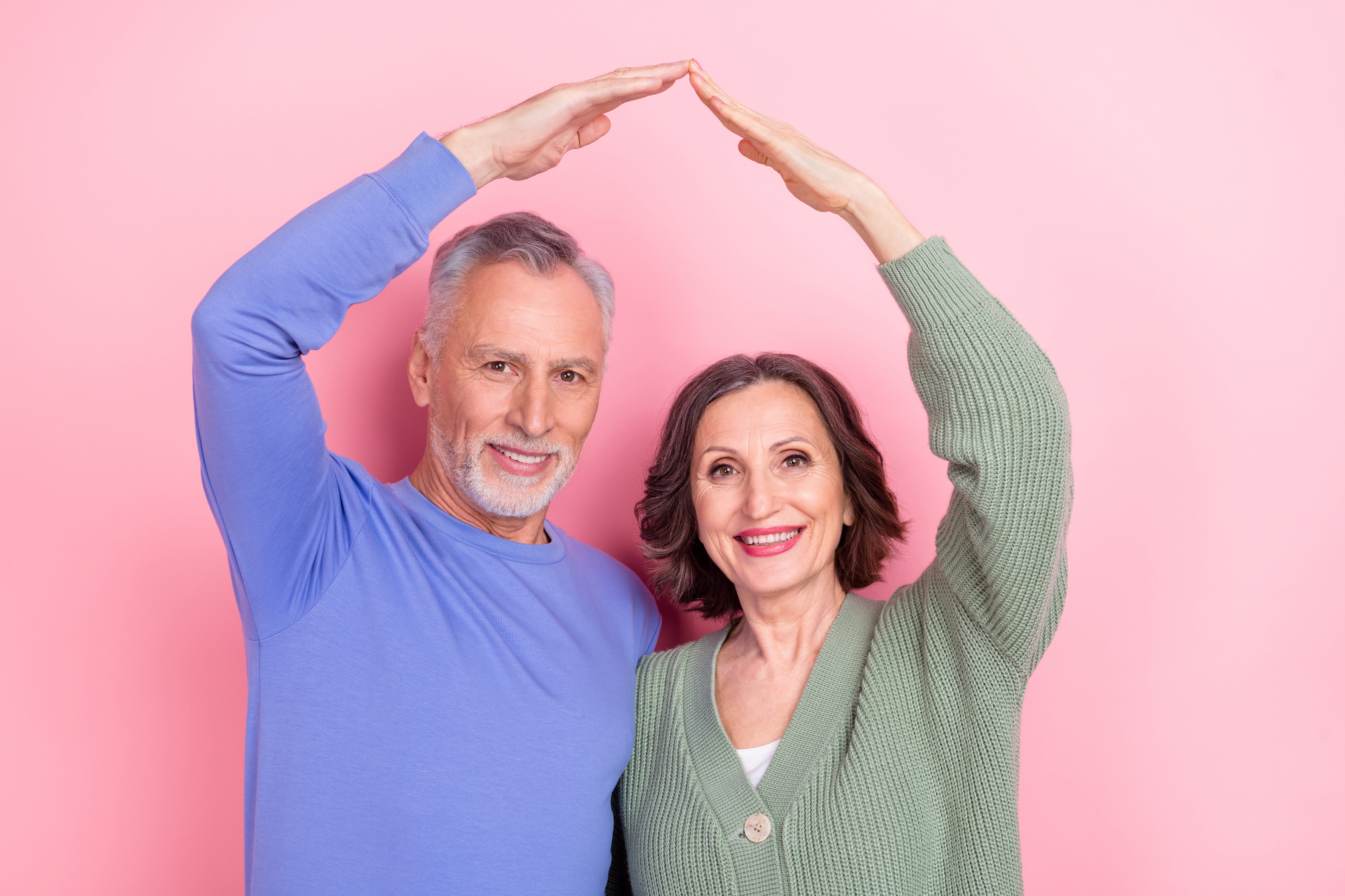 Immagine di coppia sorridente che mima il tetto di una casa con le braccia